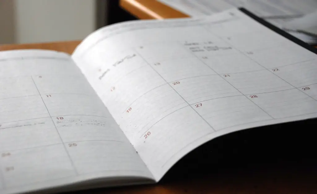 Opengeslagen maandplanner op een houten bureau