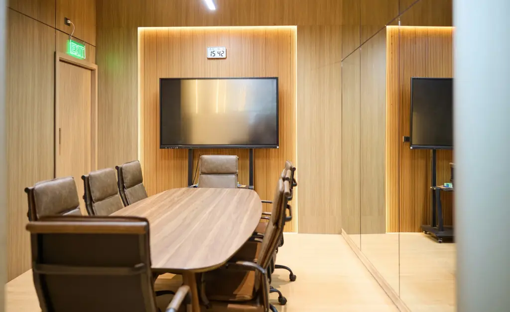 Vergaderzaal met ovale tafel, leren stoelen en scherm