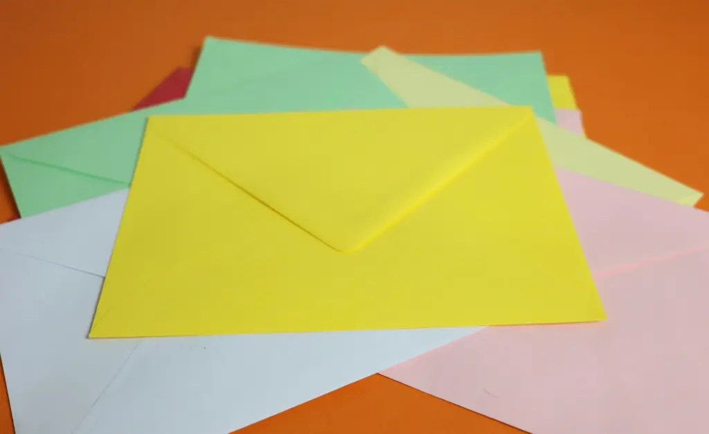 Stapel gekleurde enveloppen op een oranje ondergrond